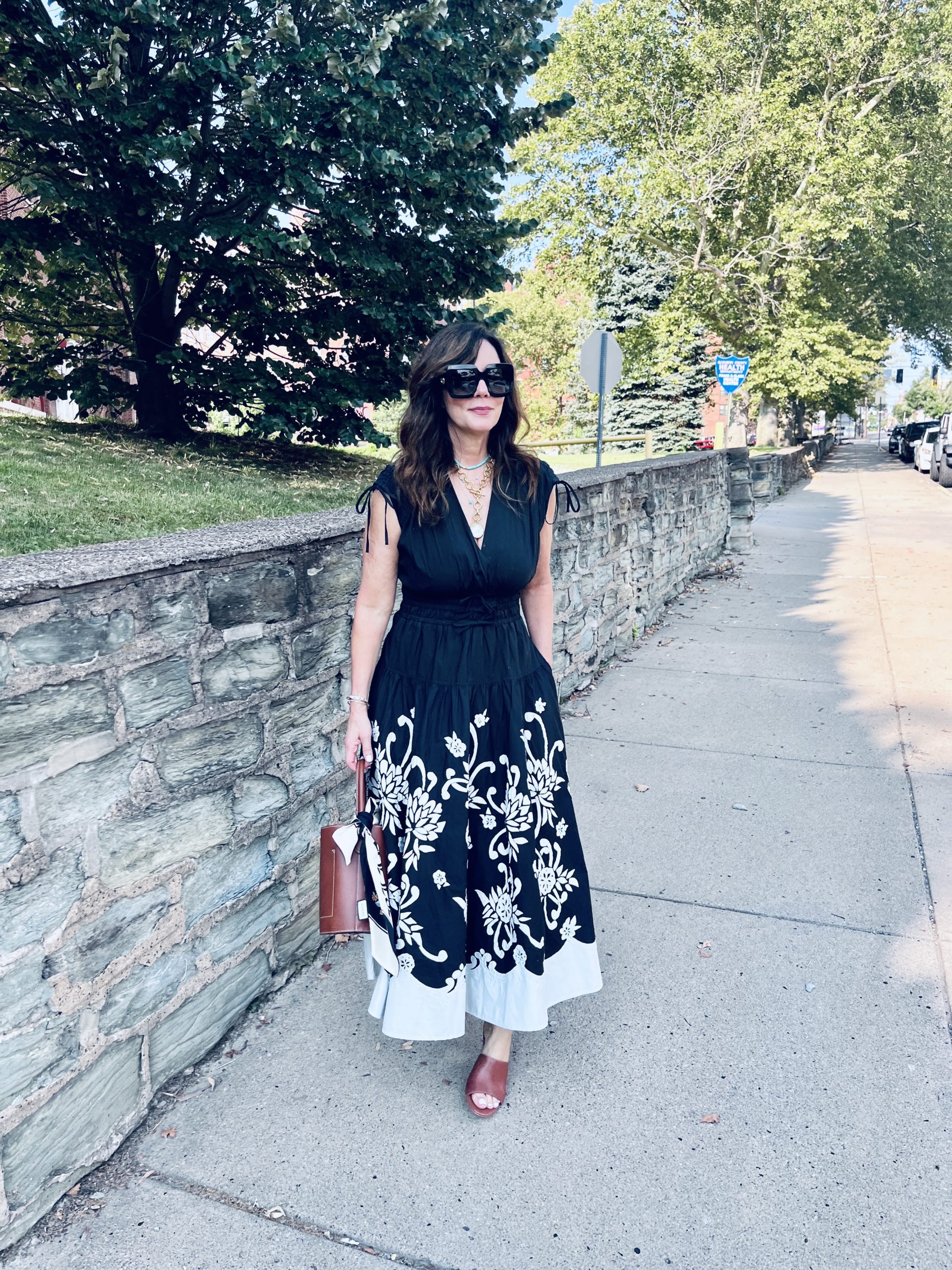 wearing a black sundress with a cognac shoe and bucket bag
